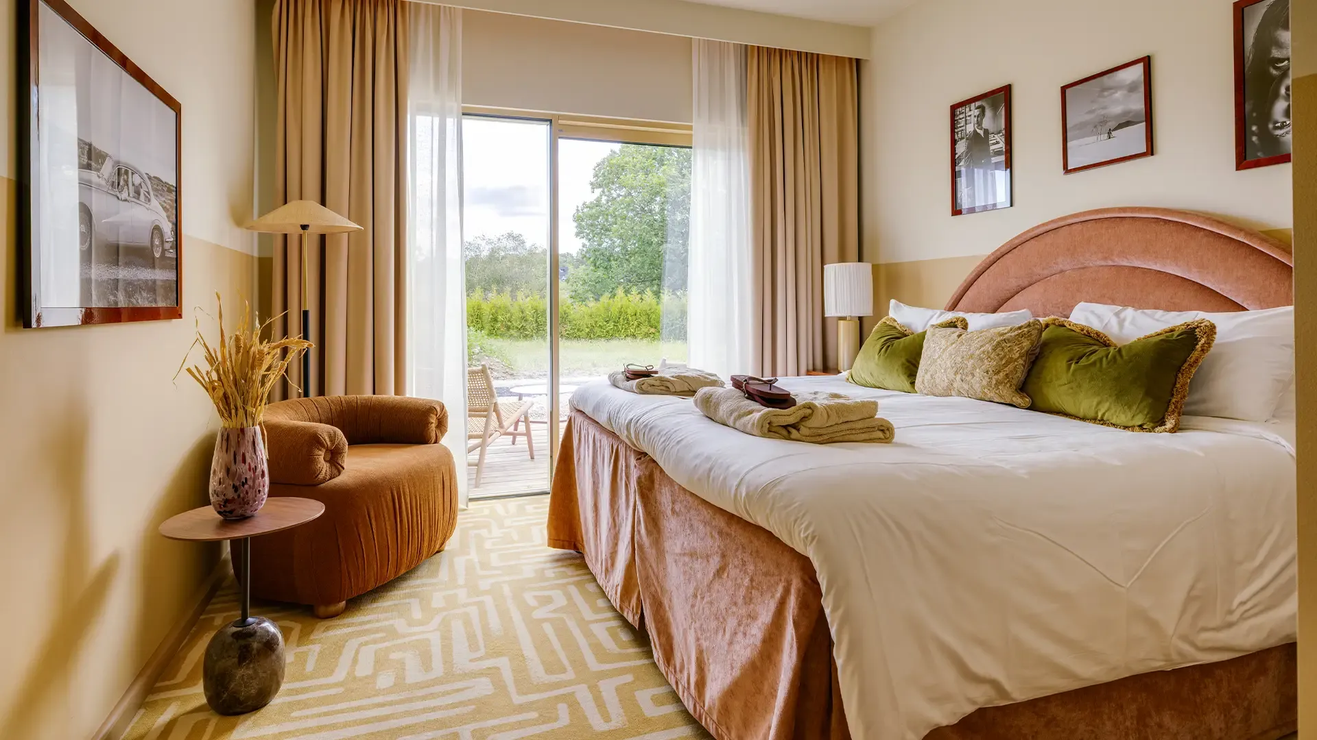 Hotellrum med dubbelsäng, fåtölj och glasdörr ut mot en uteplats