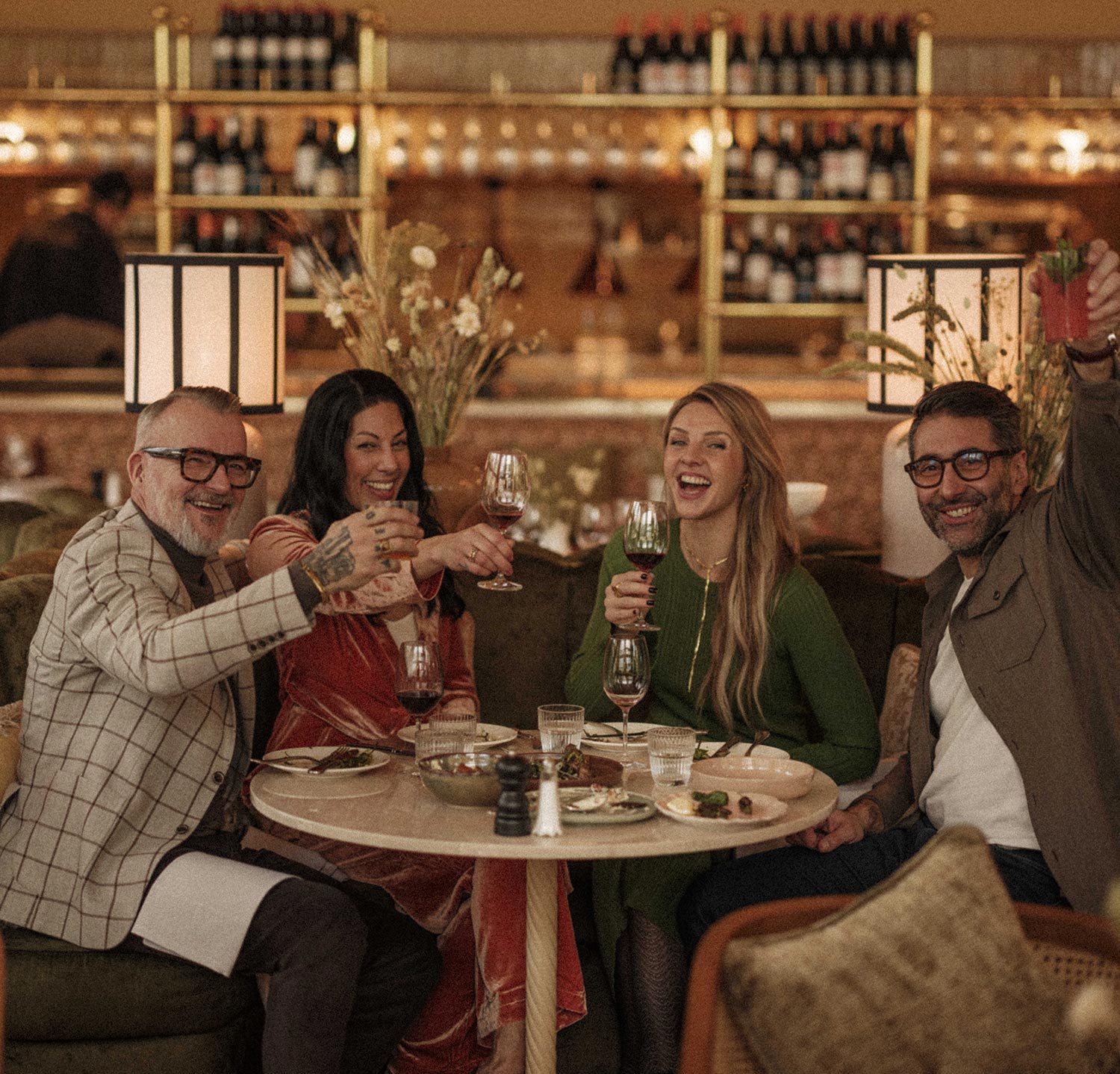Fyra vänner skålar med vin vid ett bord i restaurang Bay Bay